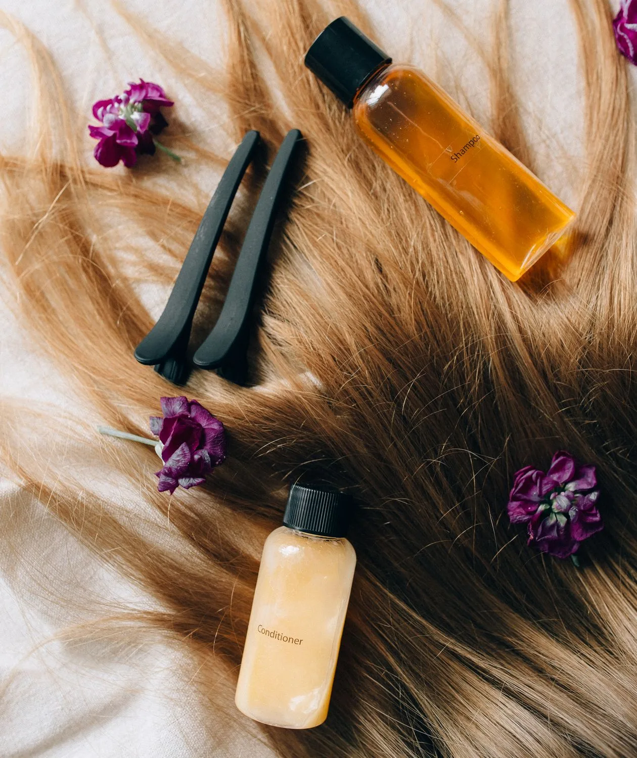 Produtos de cuidado capilar organizados sobre uma mecha de cabelo